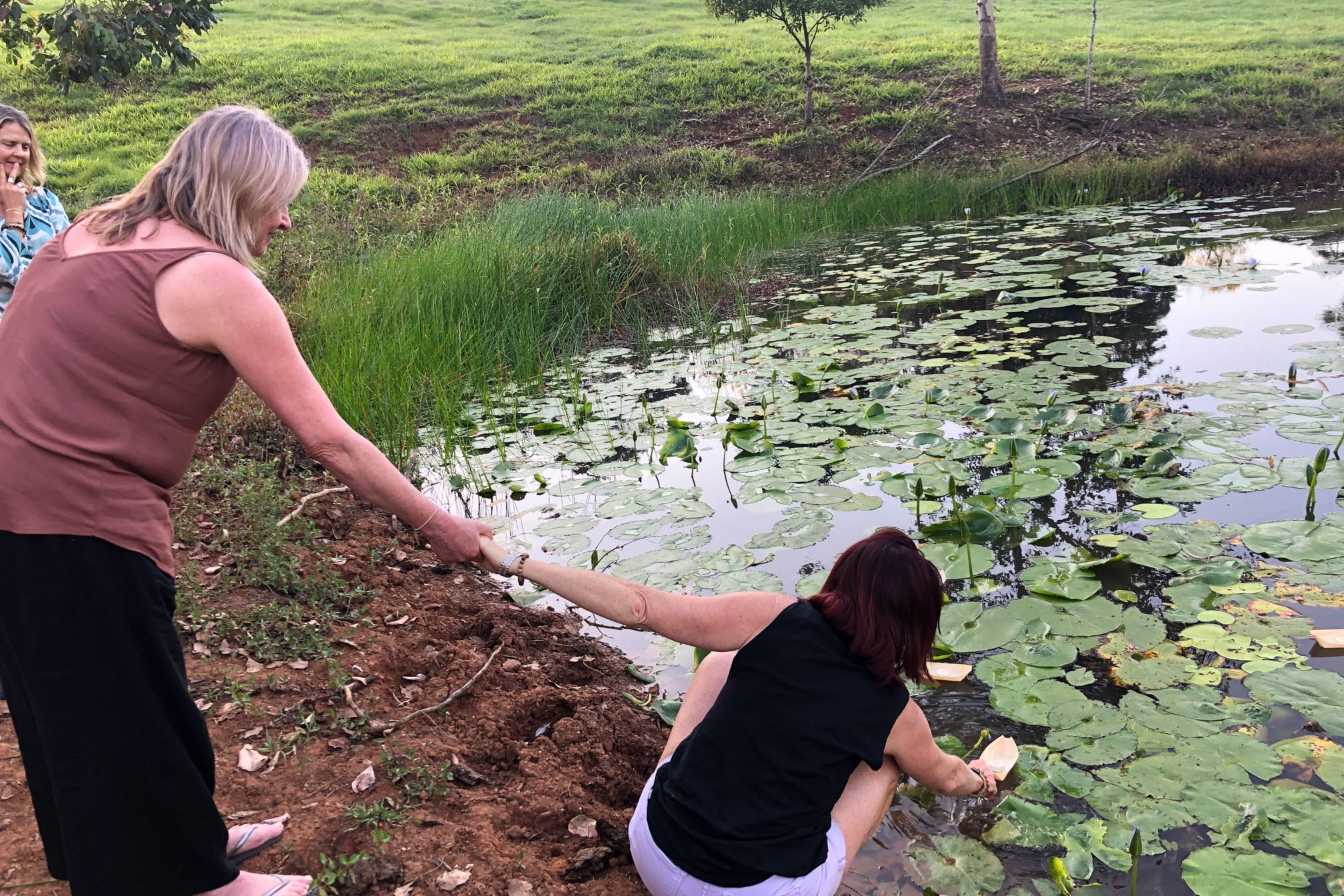 Mt Burrell Private Wellness Retreat 15 Woman helping another woman to put a paper boat on pond | Wellness Retreat Image Haven Yoga & Meditation