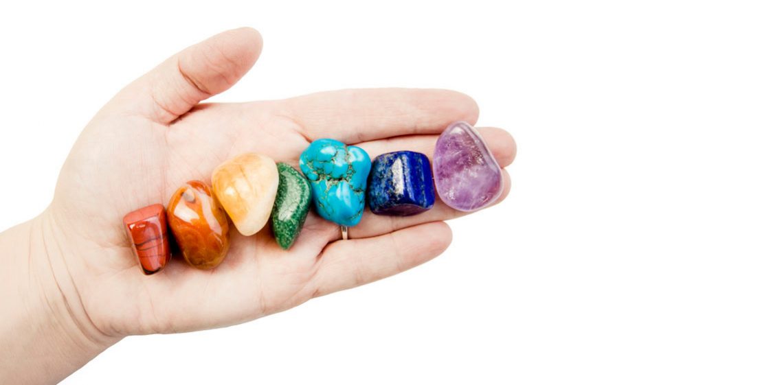 iStock-1180150756 Close up View of Woman Healer Hand Showing All Seven Chakra Color Crystal Stones in Color Order - Haven Yoga and Meditation Blog Image