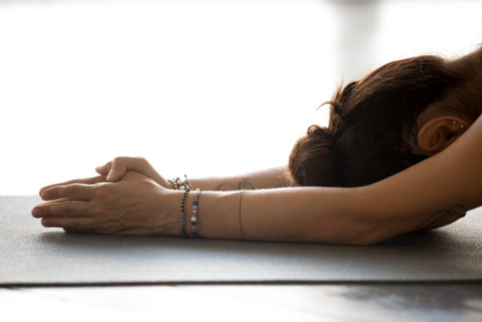 How to Manage Stress through Yoga and Meditation Woman with her hands and head on the mat - Haven Yoga and Meditation