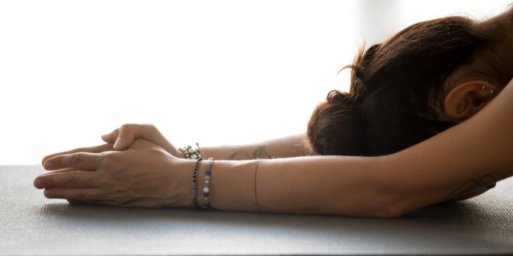 How to Manage Stress through Yoga and Meditation Woman with her hands and head on the mat - Haven Yoga and Meditation
