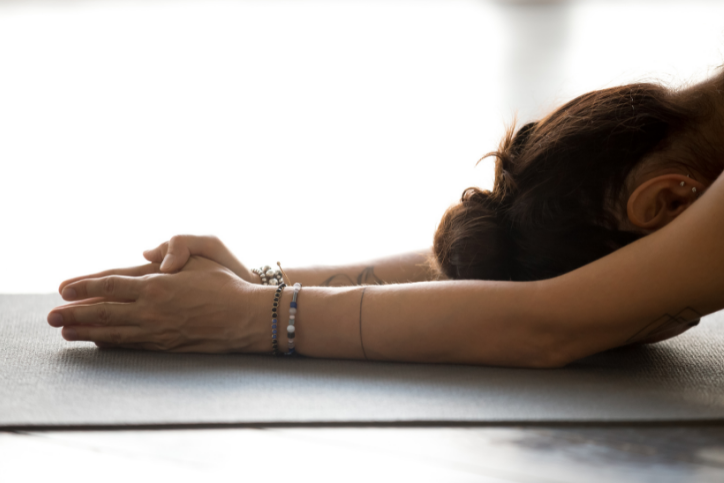 How to Manage Stress through Yoga and Meditation Woman with her hands and head on the mat - Haven Yoga and Meditation